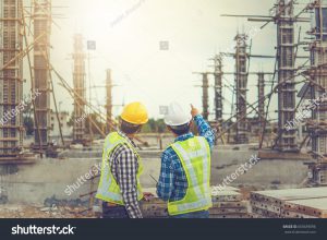 Two constructions workers pointing at job site.