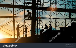 Construction workers on a job site with sun going down in background.