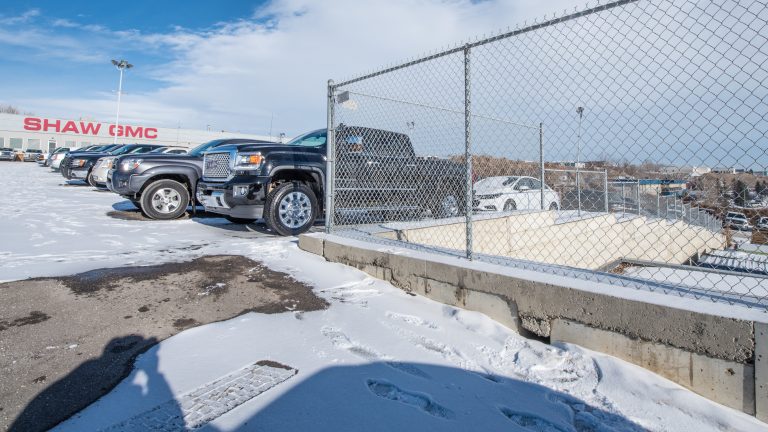 Trucks in lot next to chain link fence at Shaw GMC.