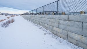 Black fence with retaining wall covered in snow at South Trail Auto Mall.
